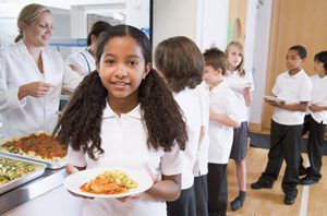 Schoolgirl-holding-plate-of-lunch-in-school-cafeteria