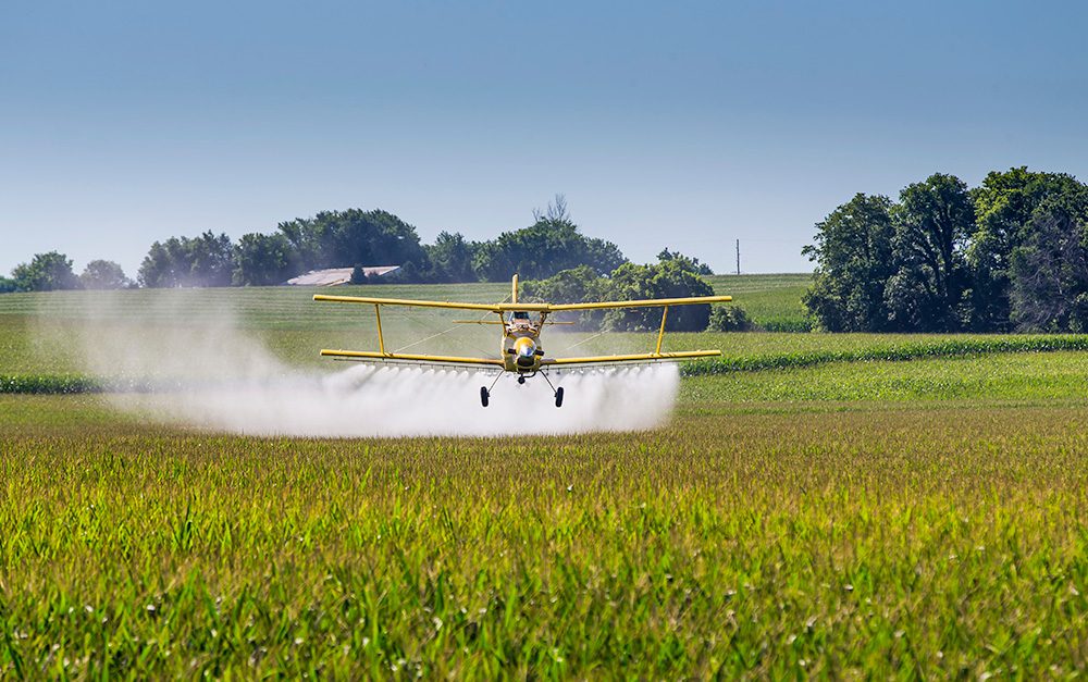 Crop duster spraying pesticides on farm