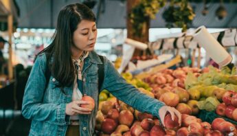 Woman shopping for fruit, questions pesticides
