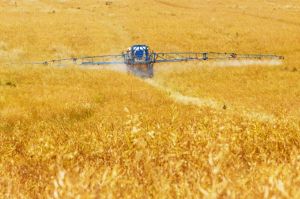 a tractor sprays pesticides on a large field