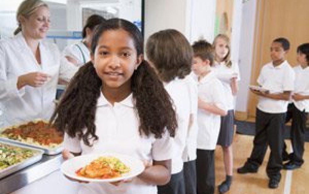 Schoolgirl-holding-plate-of-lunch-in-school-cafeteria